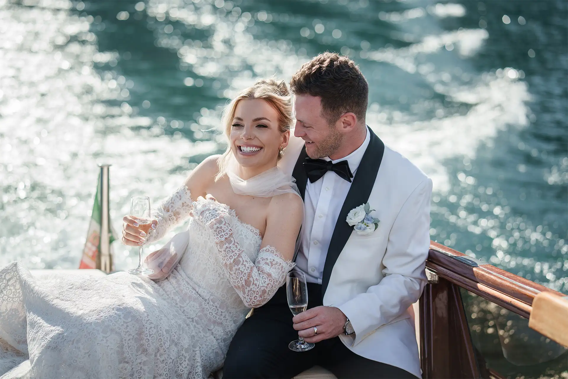 Bride and groom smiling on a wooden boat during a Lake Como wedding