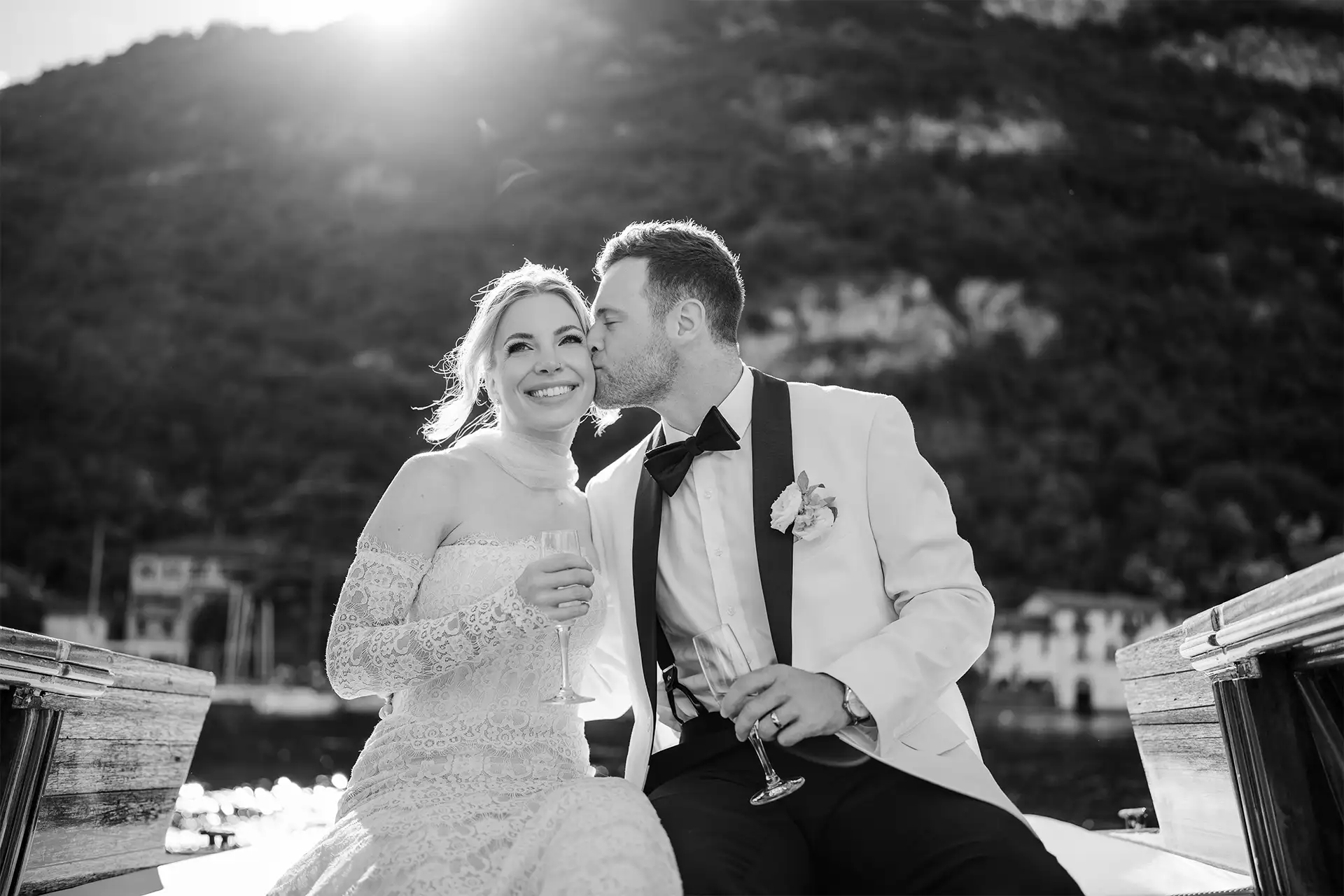 Bride and groom portrait on a wooden boat with Lake Como light behind them