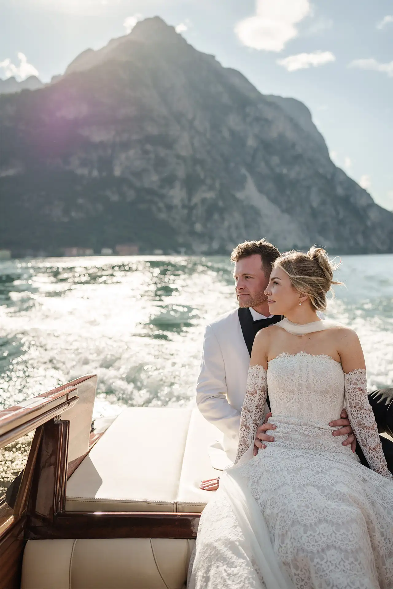 Bride and groom portrait on a wooden boat with Lake Como mountains behind them