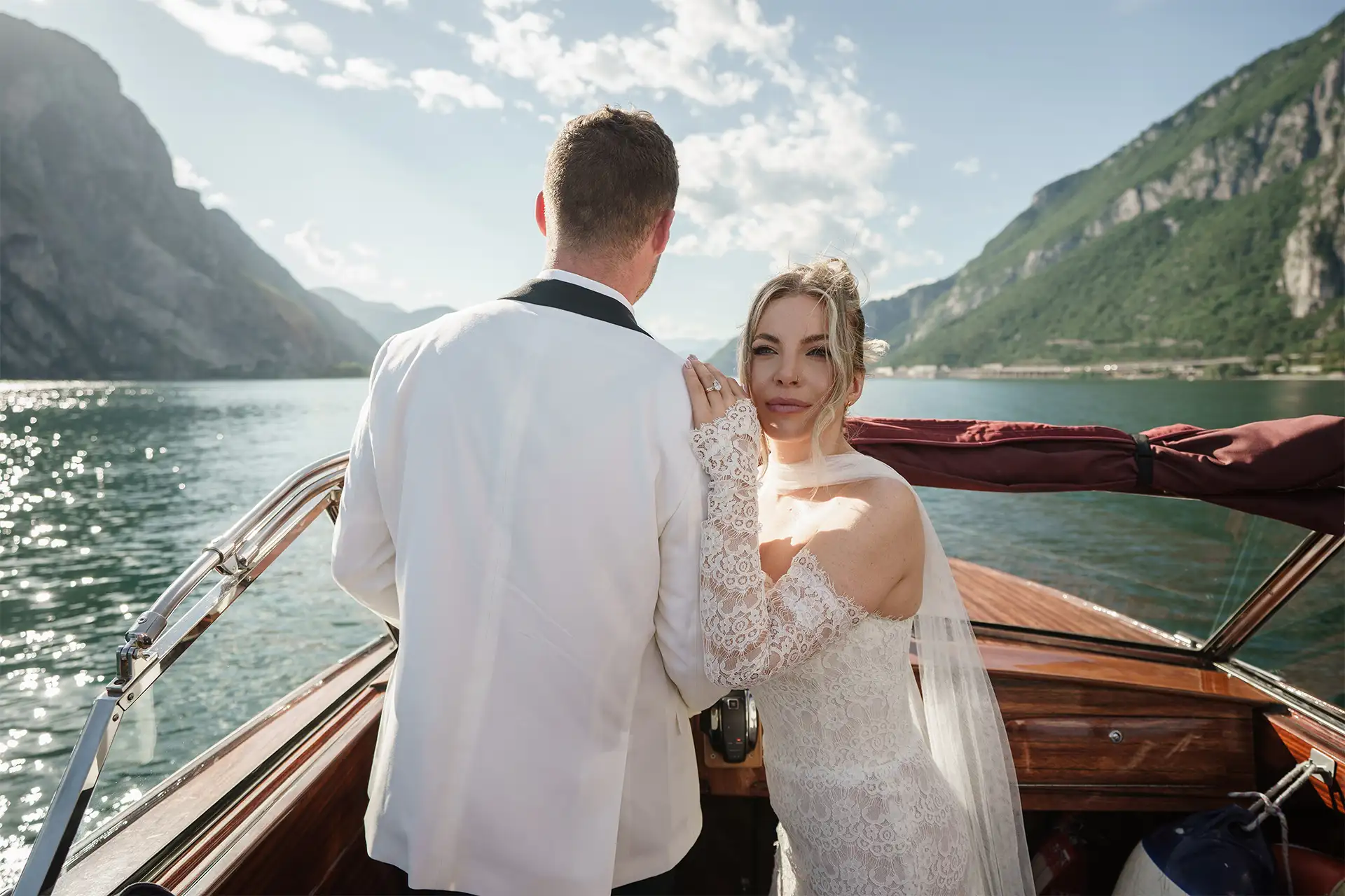 Bride standing beside the groom on a wooden boat on Lake Como